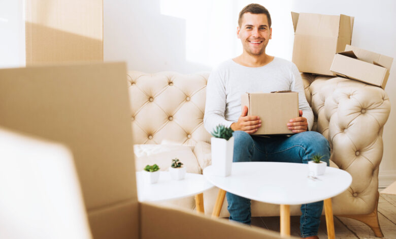 cheerful-man-apartment-with-boxes-1 - مرينا لتجارة اثاث مستعمل