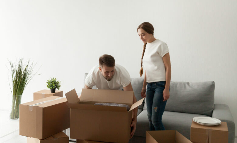 Young spouses carrying boxes relocating to new flat - مرينا لتجارة اثاث مستعمل